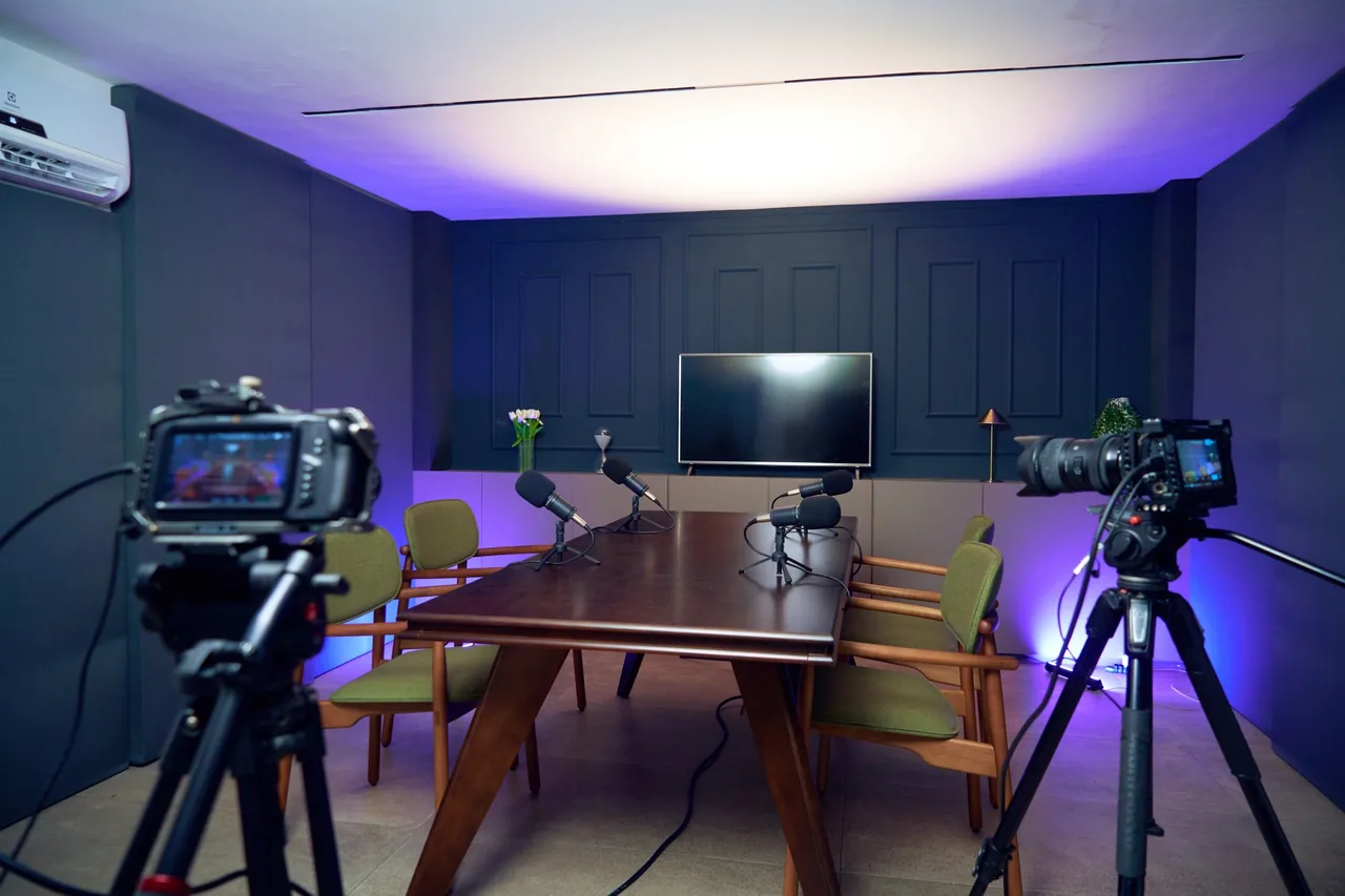 Sala do estúdio LENZ com mesa, cadeiras e câmeras montadas